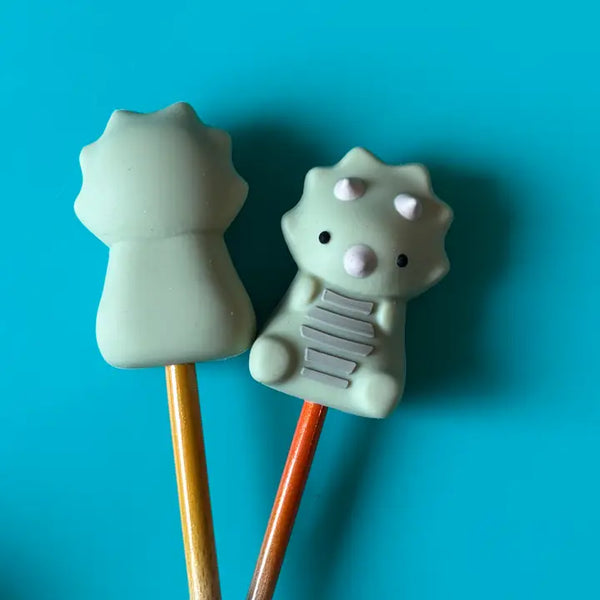 Two light grey triceratop point protectors on wooden needles on a blue background